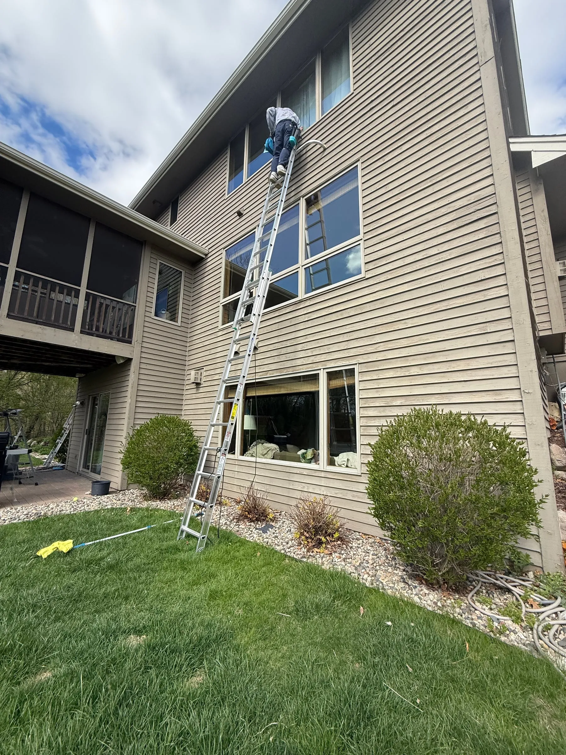 Crew member on a tall ladder cleaning second-story windows