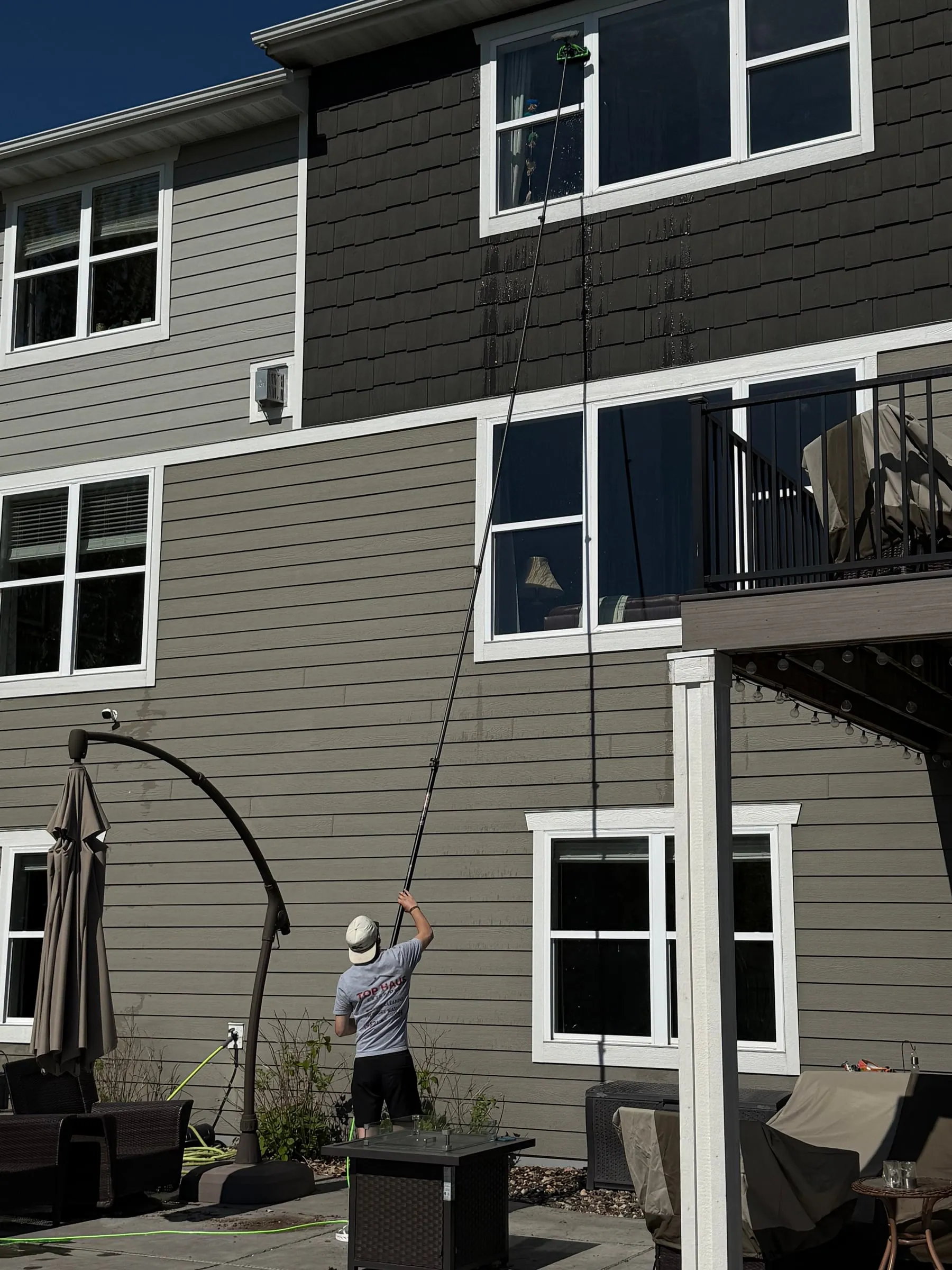 Crew member cleaning third-story windows with a water-fed pole
