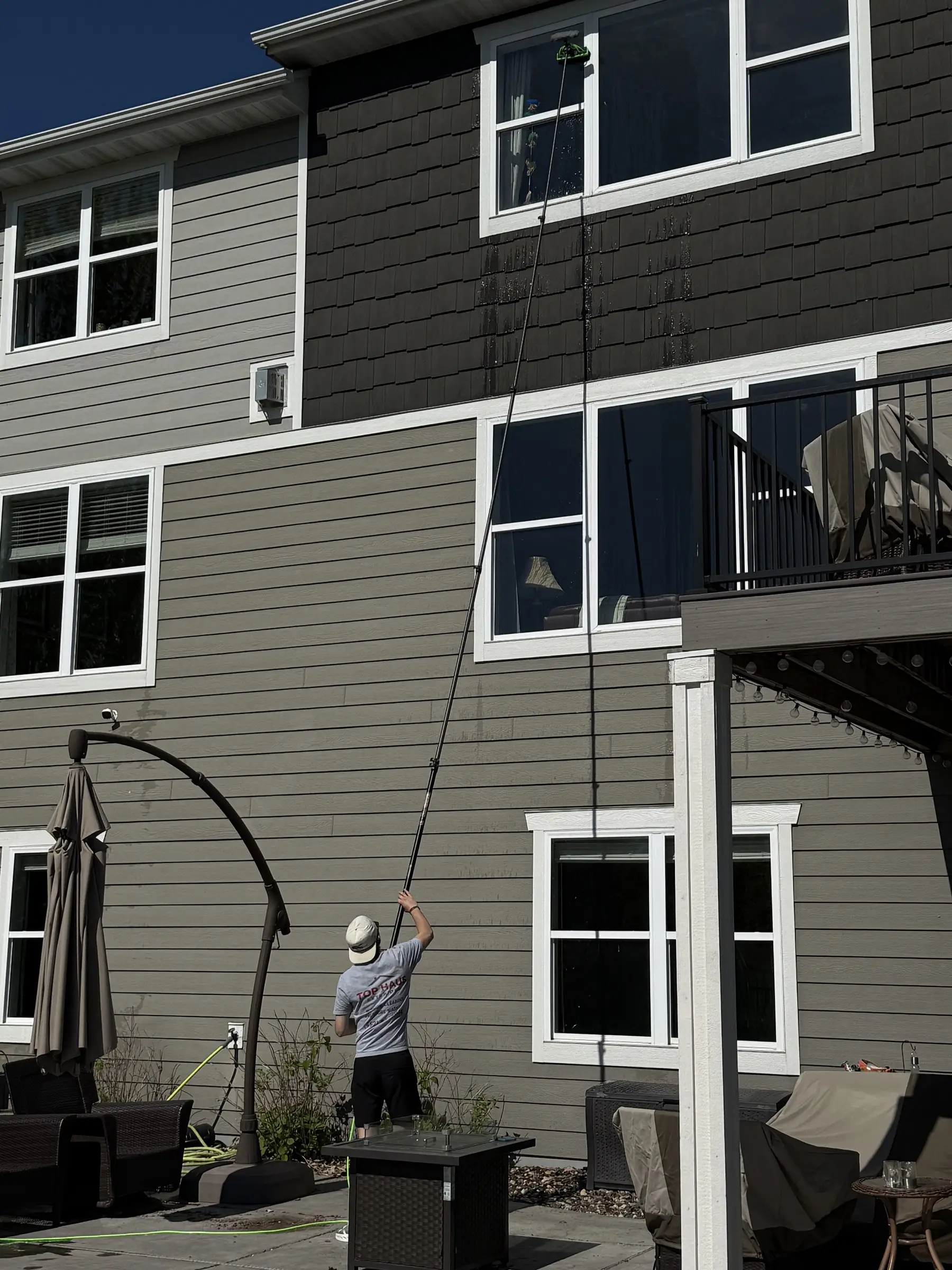 Cleaning third-story windows from the ground with a water-fed pole